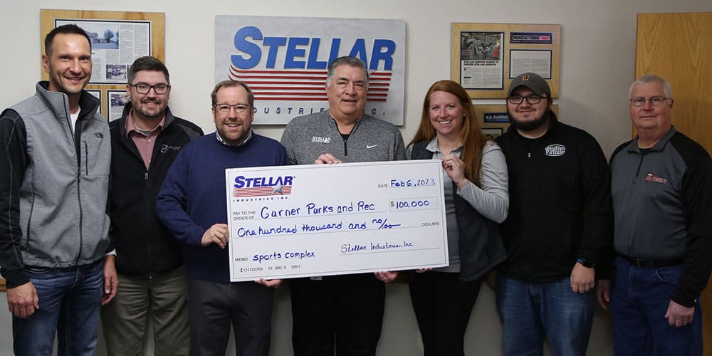 Team in front of Stellar logo showing the donation check for $100,000 made out to Garner Parks and Rec's sports complex