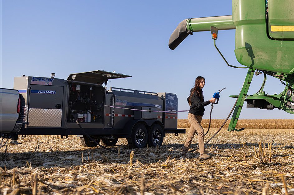 Woman fueling up agriculture equipment using stellar fuel trailer